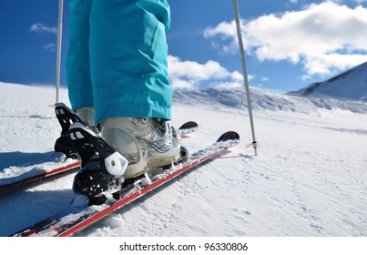 Frauenbeine in Skischuhen, die auf Alpinski stehen
