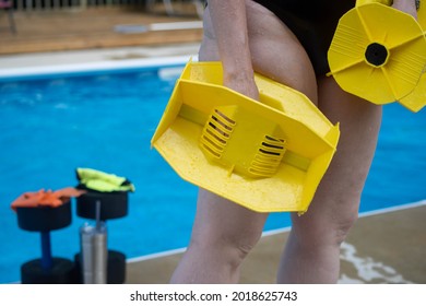 Woman's Legs In Swimsuit Carrying Aquatic Fitness Equipment With Residential Pool Background.