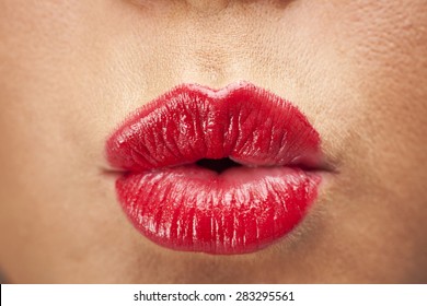 Woman's Lips Pouting And Blowing A Kiss. Wearing Bright Red Lipstick