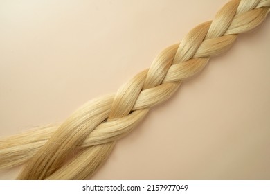 Woman's Long Blonde Hair In The Form Of The Tress Lying On A Beige Background