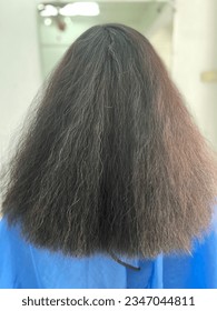 The woman's long hair is frizzy, dry and damaged, lacking nourishment.