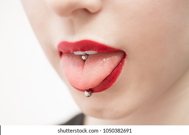 woman's mouth with red lips opened and with a piercing in a tongue	