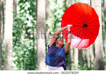 Woman's red umbrella blown away by the wind while walking alone in the park