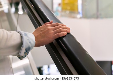 A woman's right hand is placing on the railing of escalator - Powered by Shutterstock