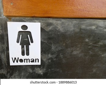 A woman's room sign on a cement floor.