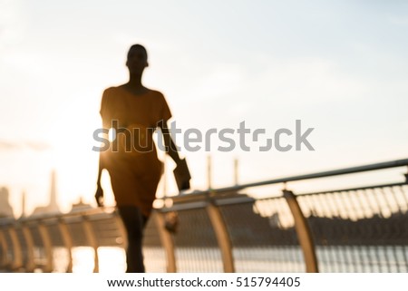 Woman's silouette walking in front of cityscape