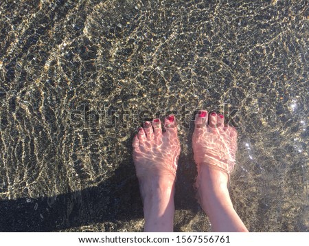 Woman's two feet under water on beach