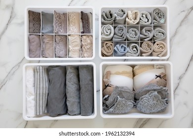 Womans Underwear, Pajamas And Socks Neatly Folded And Placed In Closet Organizer Drawer Divider On White Marble Table. Declutter Wardrobe Of Undergarments. Keeping Organized Lingerie Drawer Storage.