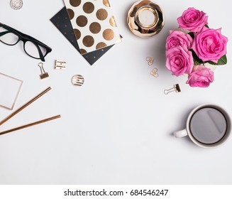 Woman's workplace with gold accessories, coffee and beautiful roses, top view