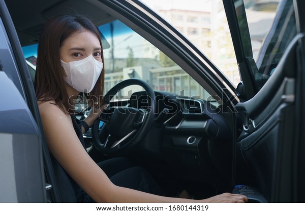 Wome wearing surgical mask in the car, for\
corona virus or Covid-19\
protection.