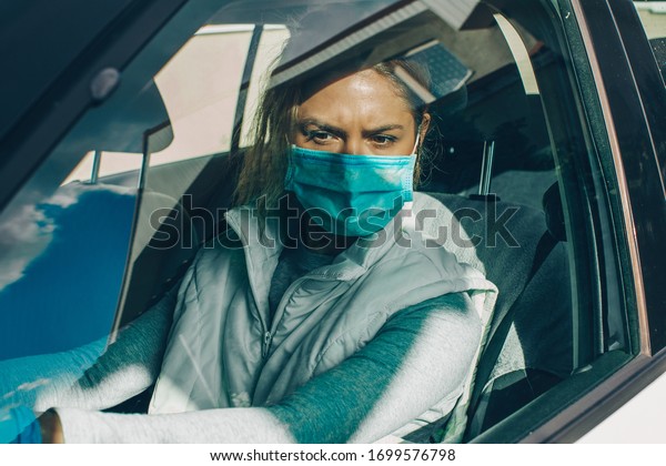 Wome wearing surgical mask in the car, for\
corona virus or Covid-19\
protection.