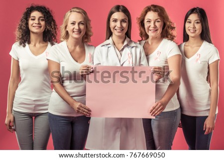 Women against breast cancer. Beautiful women of different ages and nationalities with pink ribbons on their chests are holding a pink poster and smiling, on red background