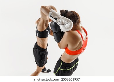 Women athletes locked in a close and fierce boxing battle, punching and standing in defensive stances isolated on white background. Concept of combat sport, martial arts, strength, endurance - Powered by Shutterstock