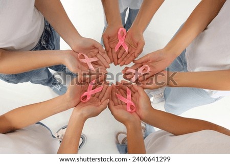 Women with awareness pink ribbons on white background, top view. Breast cancer concept