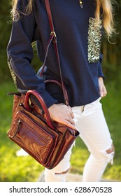 Women Bag. She Wears A Blue Sweatshirt And White Jeans.