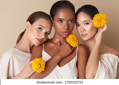 Women. Beauty And Flowers Portrait. Diversity Group Of Multi-Ethnic Models With Marigolds Standing Together. Asian, Caucasian And Mixed Race Female With Healthy, Glowing And Hydrated Skin. 