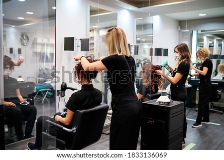 women in a beauty salon with social distance and protective masks - new normal