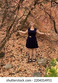 Women With Blonde Pixie Hair Throwing Leaves Into The Air In Fall Background