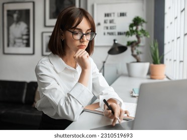 Women in business. Focused young lady manager in formal outfit, CEO sitting in front of laptop computer, working on marketing report at modern office, free space
