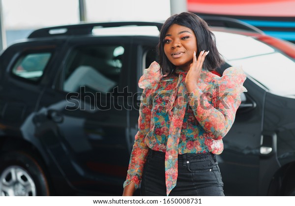 Women buying the car. Ladies in a car salon. Black\
girls near white car