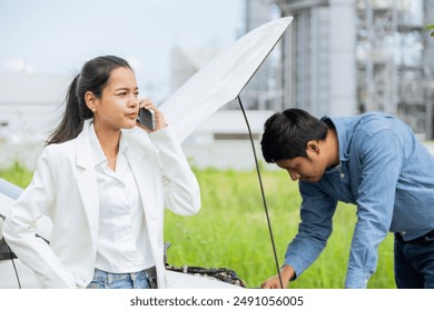 Women Car Broken on the Road. Young Couple Inspecting Car Engine on a Scenic Roadside - Powered by Shutterstock