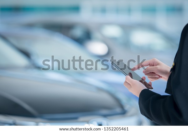 Women car\
salesmen use mobile smartphones at car showrooms. Check car sales\
in mobile phones to sell new\
cars.