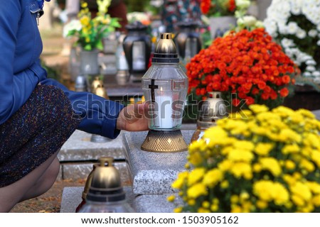 Women at the cemetery puts a candle on the grave