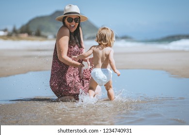 Women and child sitting in water on beautiful sunny beach