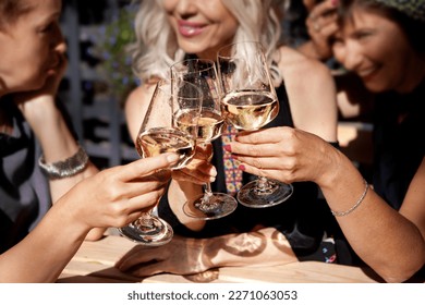 Women Clinking glasses with alcohol and toasting, party on summer terrace cafe or restaurant, celebrate holiday - Powered by Shutterstock