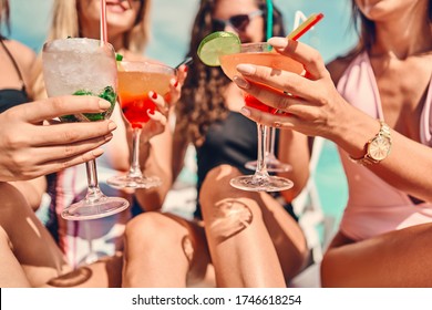 Women clinking glasses with cocktails at poolside. Close up view. Selective focus - Powered by Shutterstock