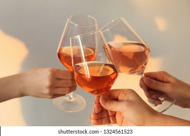 Women clinking glasses with tasty wine on light background