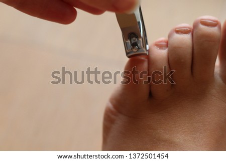 Women clipping toe nails on wooden floor 