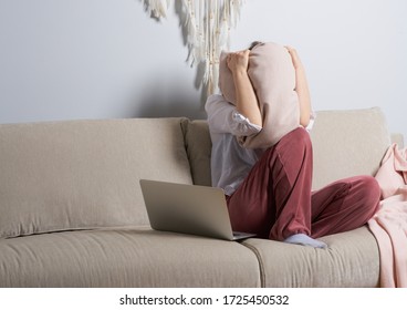 Women Close Her Face  With Pillow. Girl Stressed And Under Pressure. The Stress And Tension Are Becoming Too Much To Handle. Remote Work At Home, Female Woman On The Couch Sofa During The Day Working