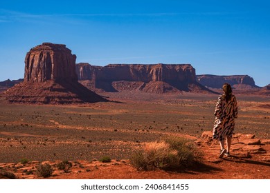 A women in colorful dress admiring the rock formations in Monument valley, USA. Blue sky and bright daylight. Orange rocks, spring time. - Powered by Shutterstock