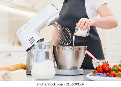 A women cook adds a milk to prepare dough or cream in a mixer bowl. cooking courses. bread and dessert recipes. family business. online lessons for cooks. - Powered by Shutterstock