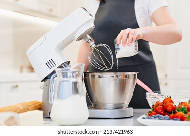 A women cook adds a milk to prepare dough or cream in a mixer bowl. cooking courses. bread and dessert recipes. family business. online lessons for cooks. - Powered by Shutterstock