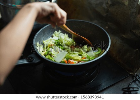 women cooking fried vegetables in the kitchen