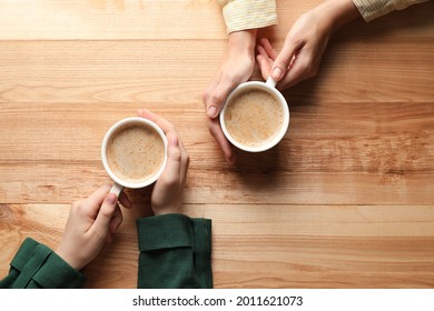 Women With Cups Of Coffee At Wooden Table, Top View