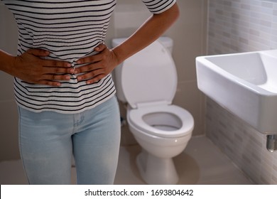 Women with Cystitis problems in front of the toilet bowl handle the belly want to pee , concept of incontinence