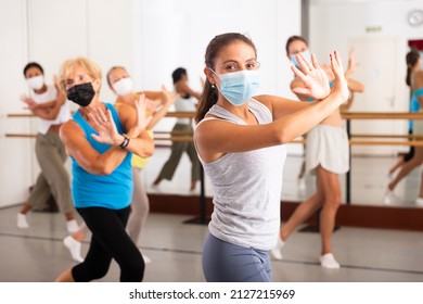 Women of different ages in face masks dancing together during their group training.