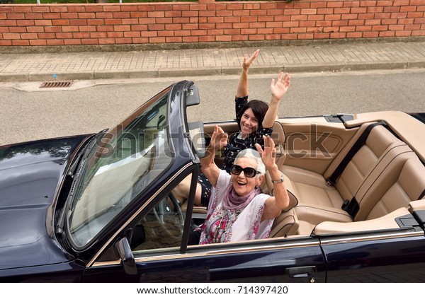 women\
of different generations happy in a convertible\
car