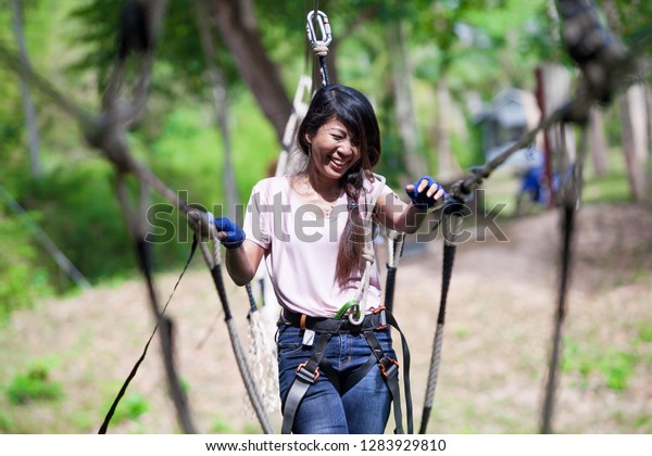 Women Do Challenging Adventure Activities on the Rope.\
The woman was laughing Insists on a Bridge Walkway made of Rope\
\

