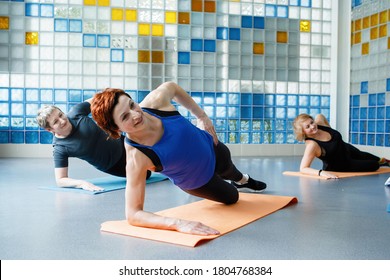 Women Do Side Plank On One Arm On A Yoga Or Fitness Mat In The Gym.