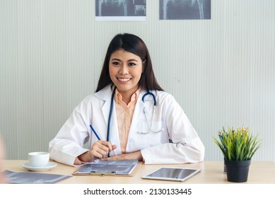 Women Doctor Using Laptop Tablet Telemedicine Vdo Call Conference With Patient. Women Doctor Write Prescription Medical Lab Working Medical Clinic Looking CAT Scan Xray Film. Women Doctor Office Desk