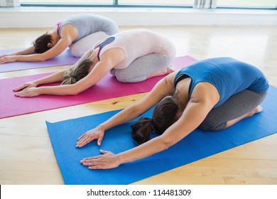 Women doing childs pose in yoga class in fitness studio