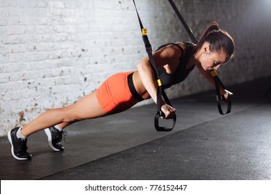 Women doing push ups training arms with trx fitness straps in gym