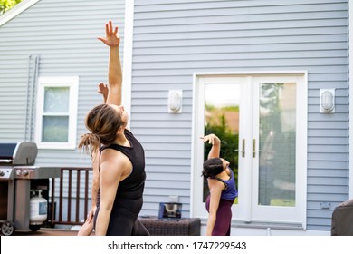 Women Doing A Virtual Yoga Class At Home Outside During COVID-19 Coronavirus Pandemic.  Social Distancing While Practicing Yoga.