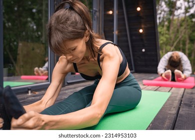 Women doing yoga stretching on yoga mat at terrace - Shutterstock ID 2314953103