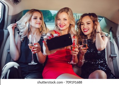 Women drinking champagne and make selfie in a limousine car. - Powered by Shutterstock