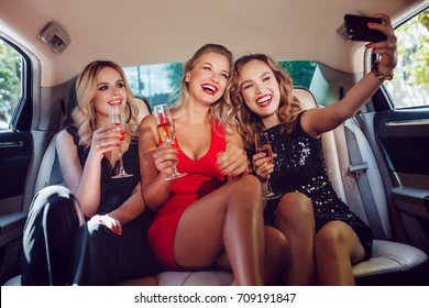 Women drinking champagne and make selfie in a limousine car. - Powered by Shutterstock